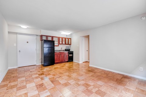 a kitchen with a black refrigerator and wooden floors